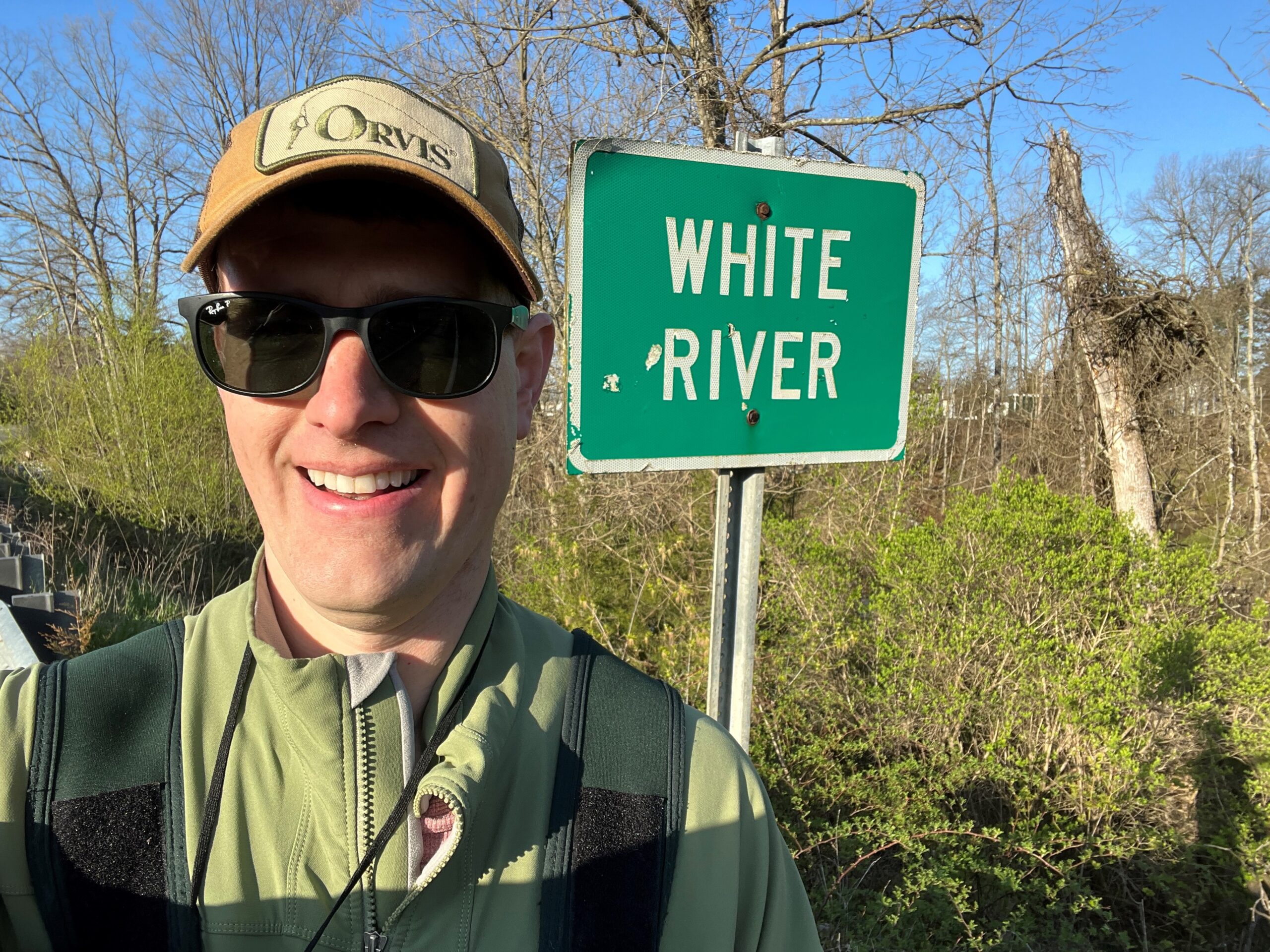 Man standing next to White River Sign